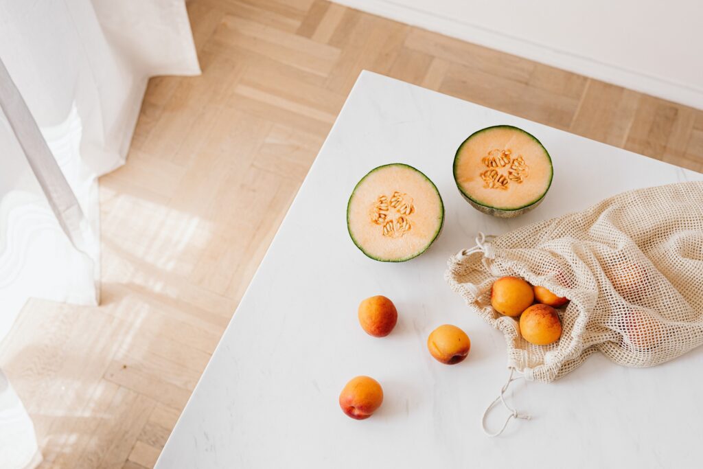 Melon and peaches next to a biodegradable bag, a type of Biodegradable Trending Products